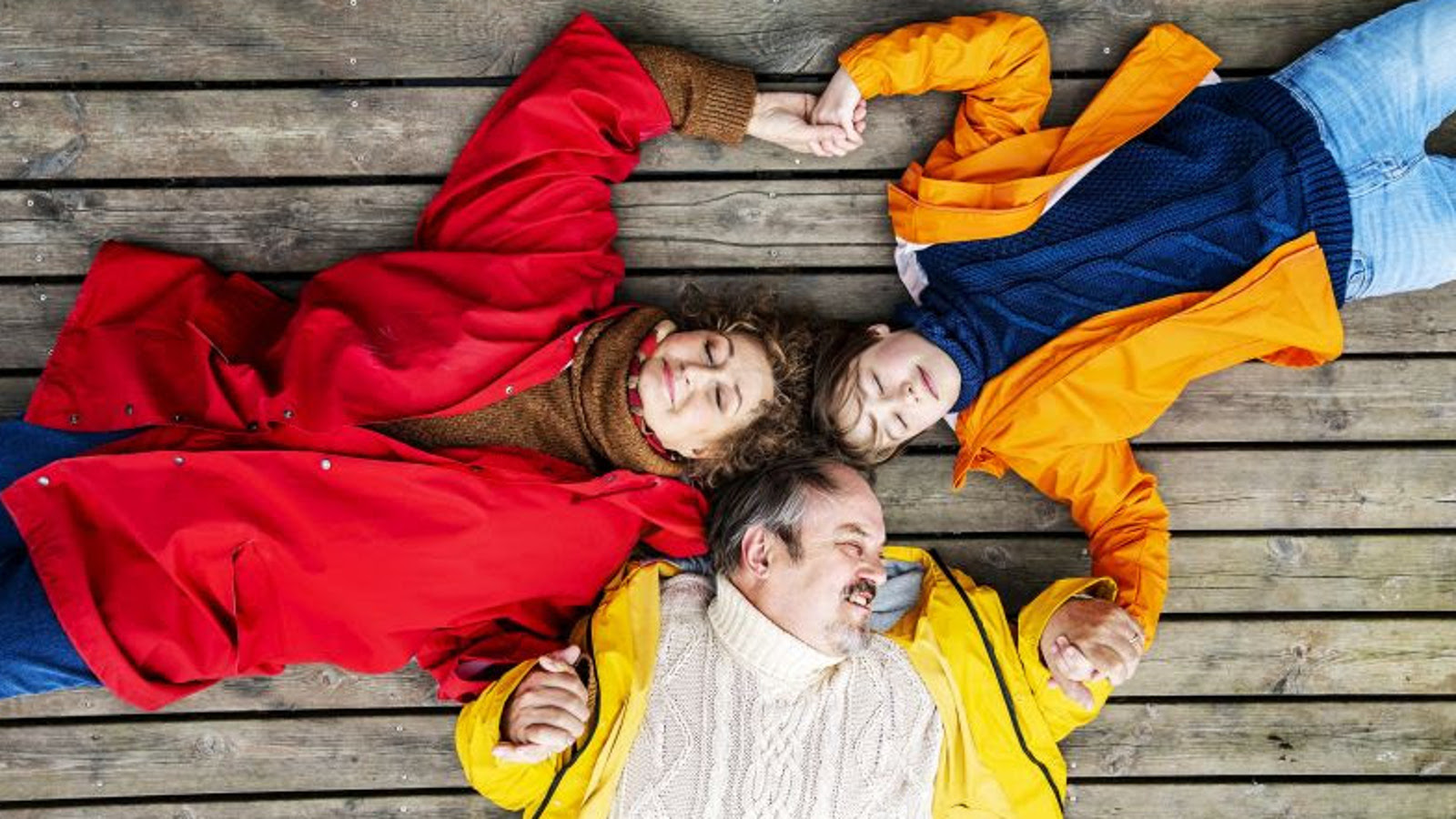 Kuvassa ovat ylhäältä päin kuvattuna punaisessa takissa Heidi Herala, keltaisessa takissa ja valkoisessa villapaidassa Juhani Laitala ja punaisessa takissa ja tumman sinisessä puserossa tytärtä esittävä näyttelijä. He makaavat lattialla.  