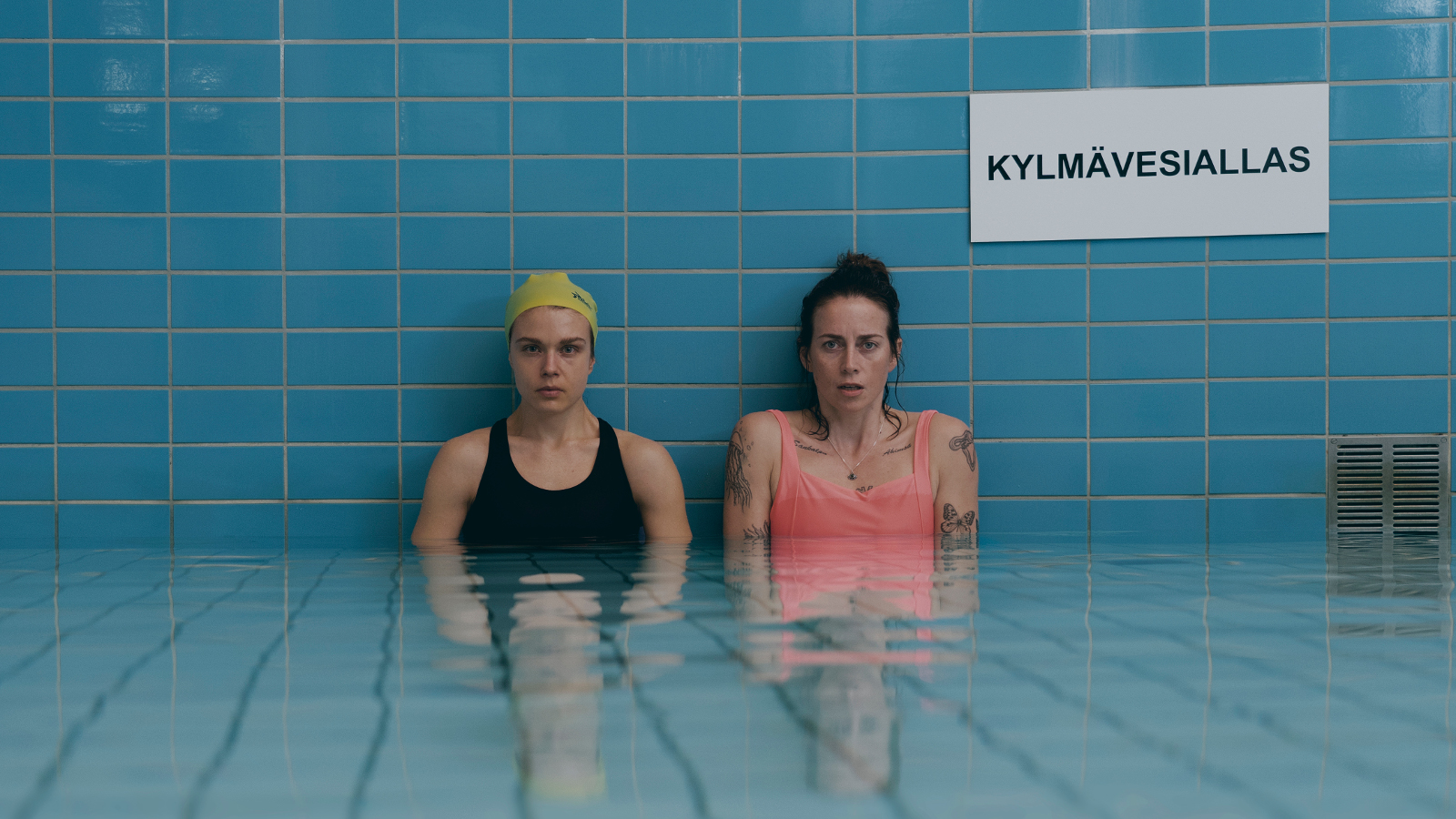 Kuvassa ovat seisomassa Alina Tomnikov ja Iina Kuustonen turkoosissa vesialtaassa vyötäröä myöten. Seinällä on kyltti kylmävesiallas.