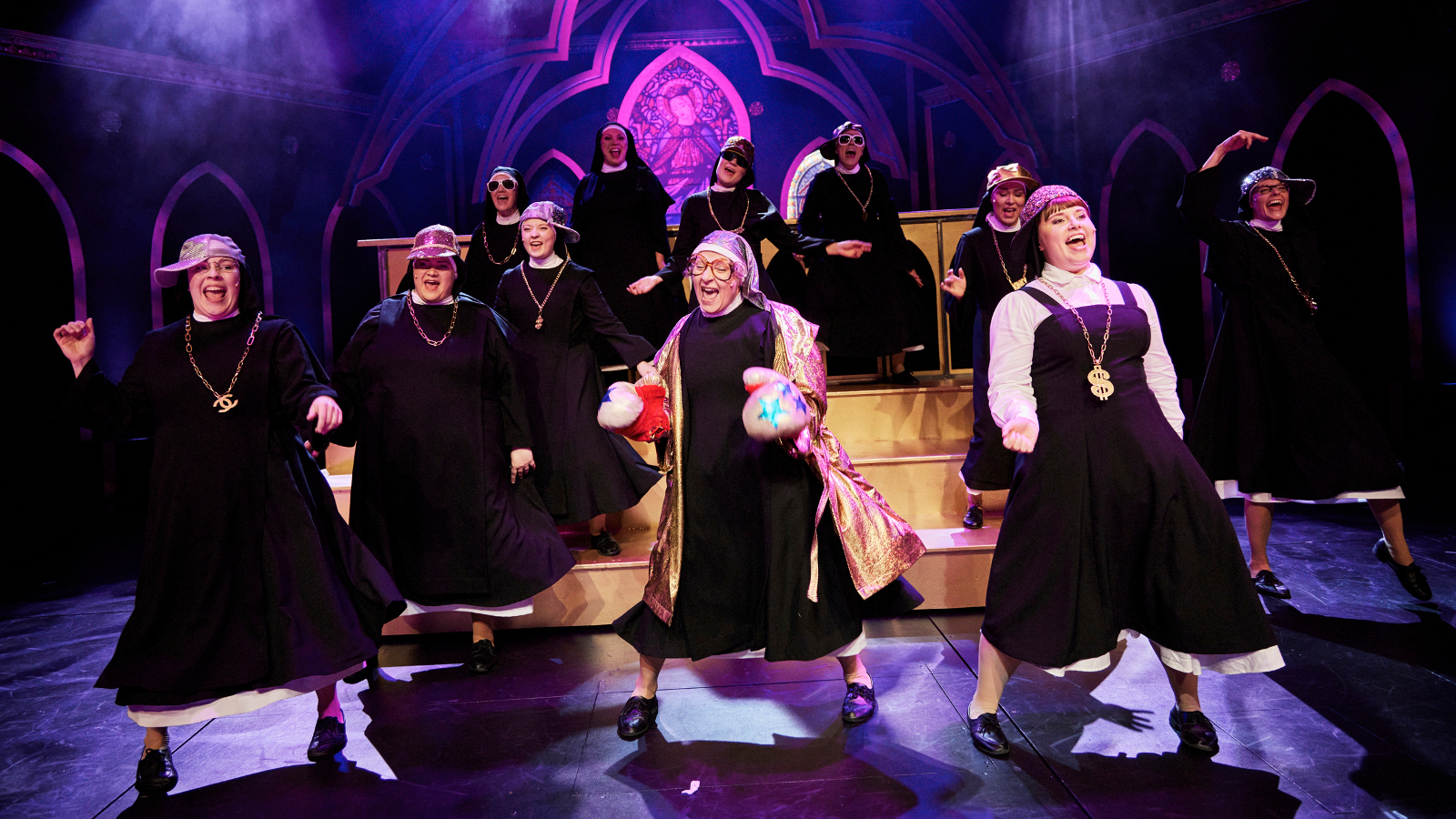 Kuvassa on yksitoista nunnaa helmat liehuen laulamassa mustissa kaavuissaan.