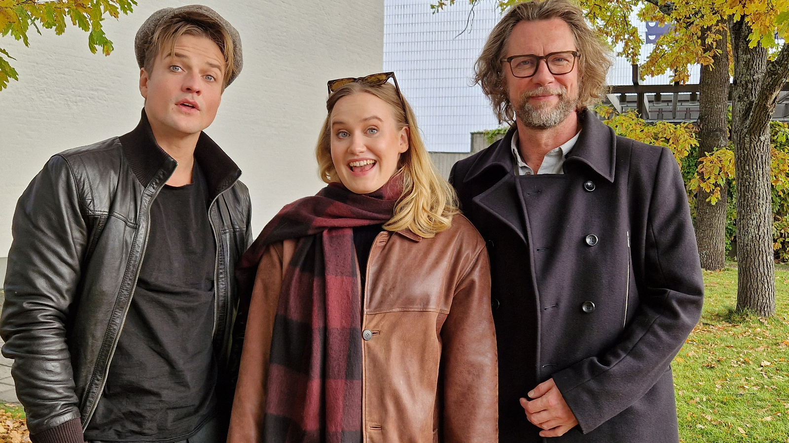 Kuvassa ovat Mikael Saari mustassa nahkatakissa, Aurora Manninen ruskeassa nahkatakissa ja Antti Reini mustassa takissa. Kuva on puolivartalokuva ja otettu ulkona.