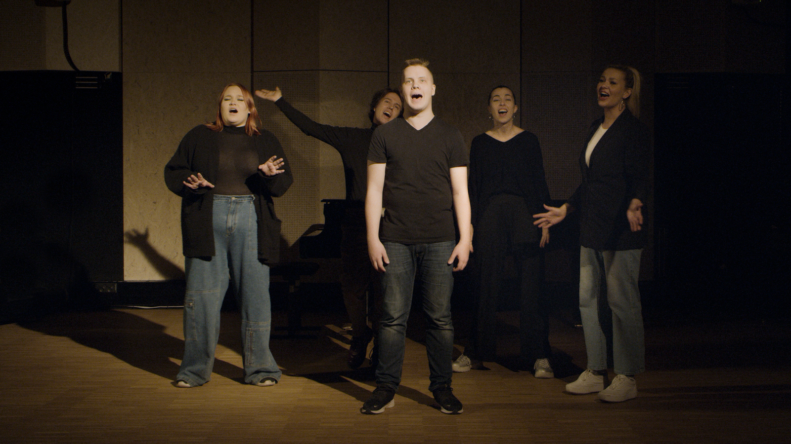 Kuvassa ovat Hoosiannan viisi laulajaa tummahkossa kuvassa ja yksi heistä on keskellä kuvaa.
