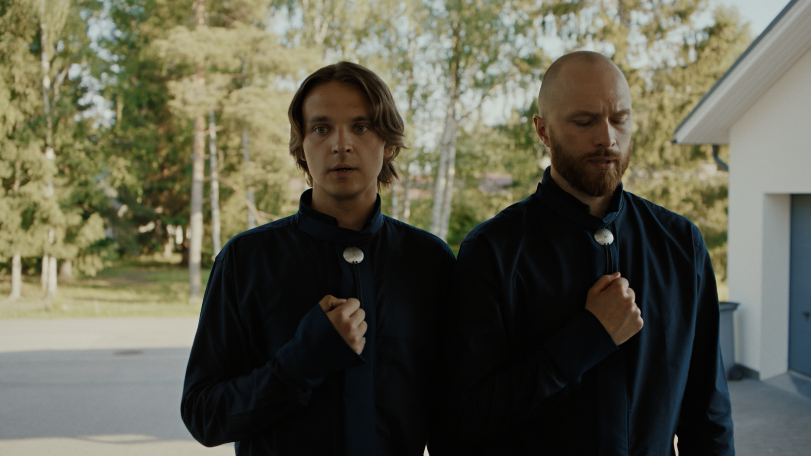 Kuvassa ovat Roope Salminen ja Eino Heiskanen seisomassa pihalla, jonka taustalla näkyy vihreitä lehtipuita. 