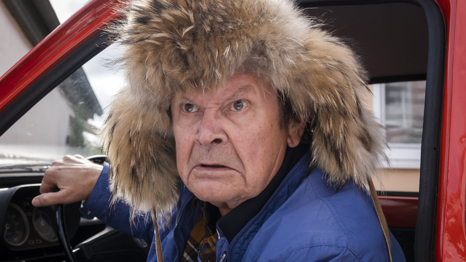 Kuvassa on Heikki Kinnunen Escortia kuljettamassakarvahattu päässään.  Kuva on kasvokuva.