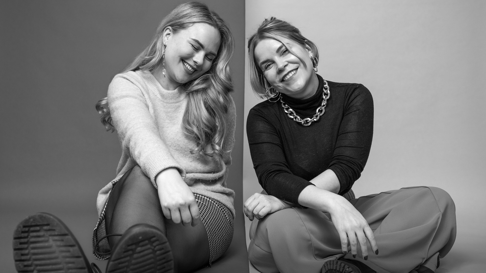 Kuvassa ovat vasemmalla Laura Wathén ja oikealla Katri Ylinen eri kuvissa istumassa lattialla iloisilla ilmeillä. Kuva on musta-valkoinen.
