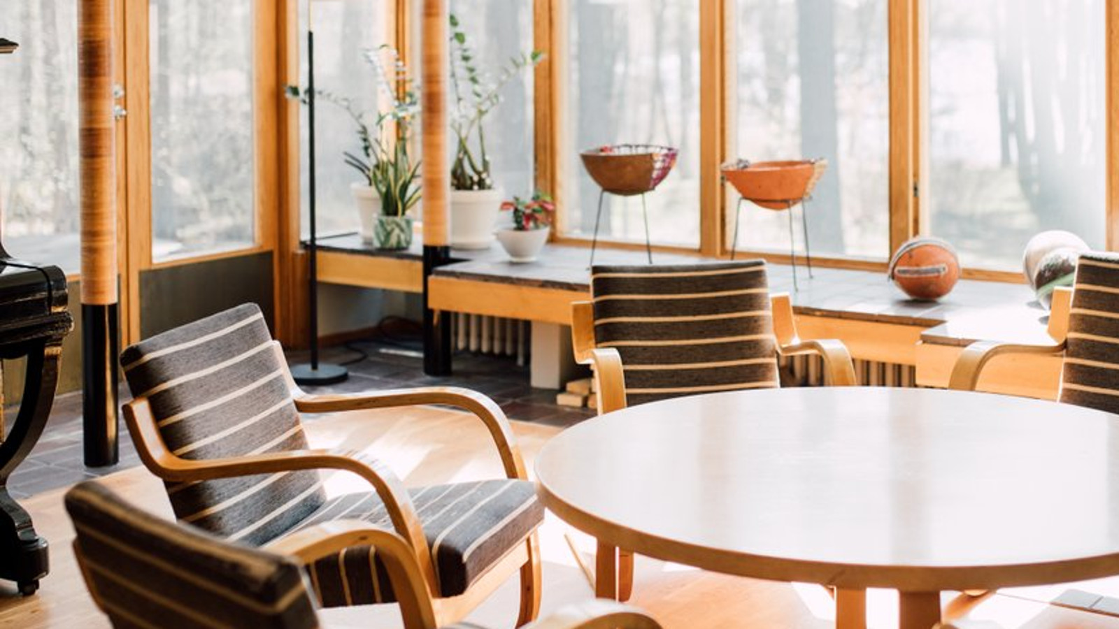 Kuvassa on näkymä Alvar Aallon suunnittelemasta Kantolan talosta.  Kuvassa on etualalla musta-valkoisten nojatuolien ja pöydän ryhmä ja näkymä ulos pystyrimoitetuista kapeahkoista ikkunoista, joita on monta.
