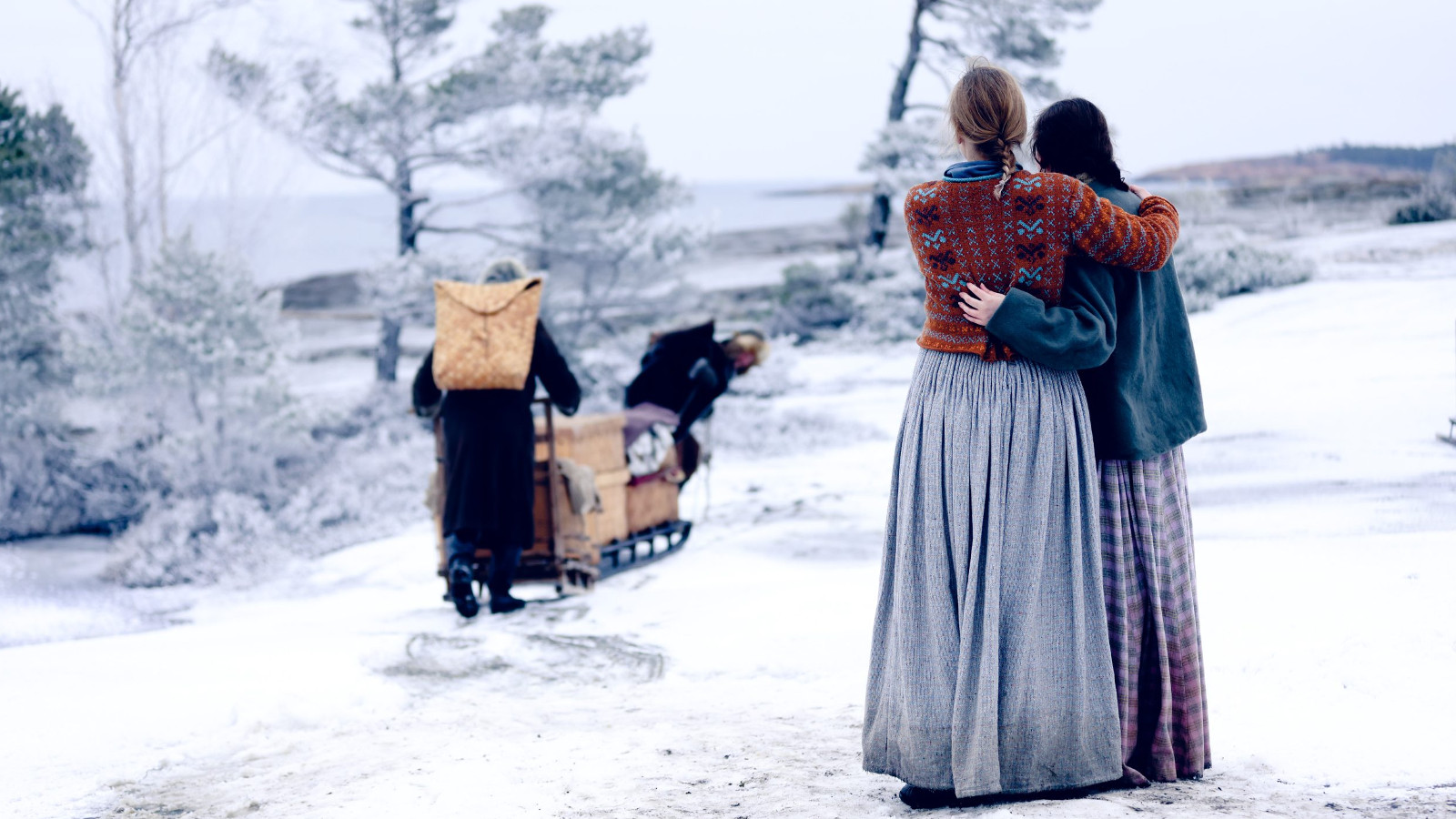 Kuvassa on talvi ja Maija ja tytär Maria ovat selin ja katsovat lähteviä Jannea ja Augustia.  Jannella on tuohikontti selässään ja he työntävät tavaraa täynnä olevaa kelkkaa Augustin kanssa.