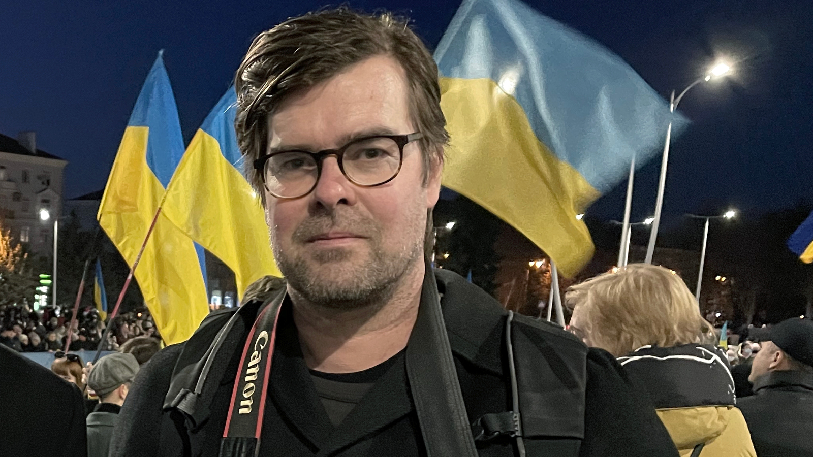 Kuvassa on Antti Hämälinen kameran kanssa ja taustalla liehuvat sini-keltaiset ukrainan liput.