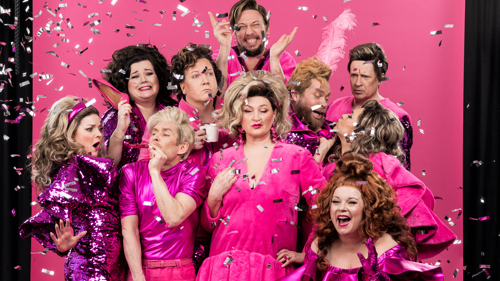 Kuvassa ovat näyttelijät tiiviisti keskellä olevan vaaleatukkaisen naisnäyttelijän ympärillä. Hänella on pinkki puki ja tausta on pinkki.