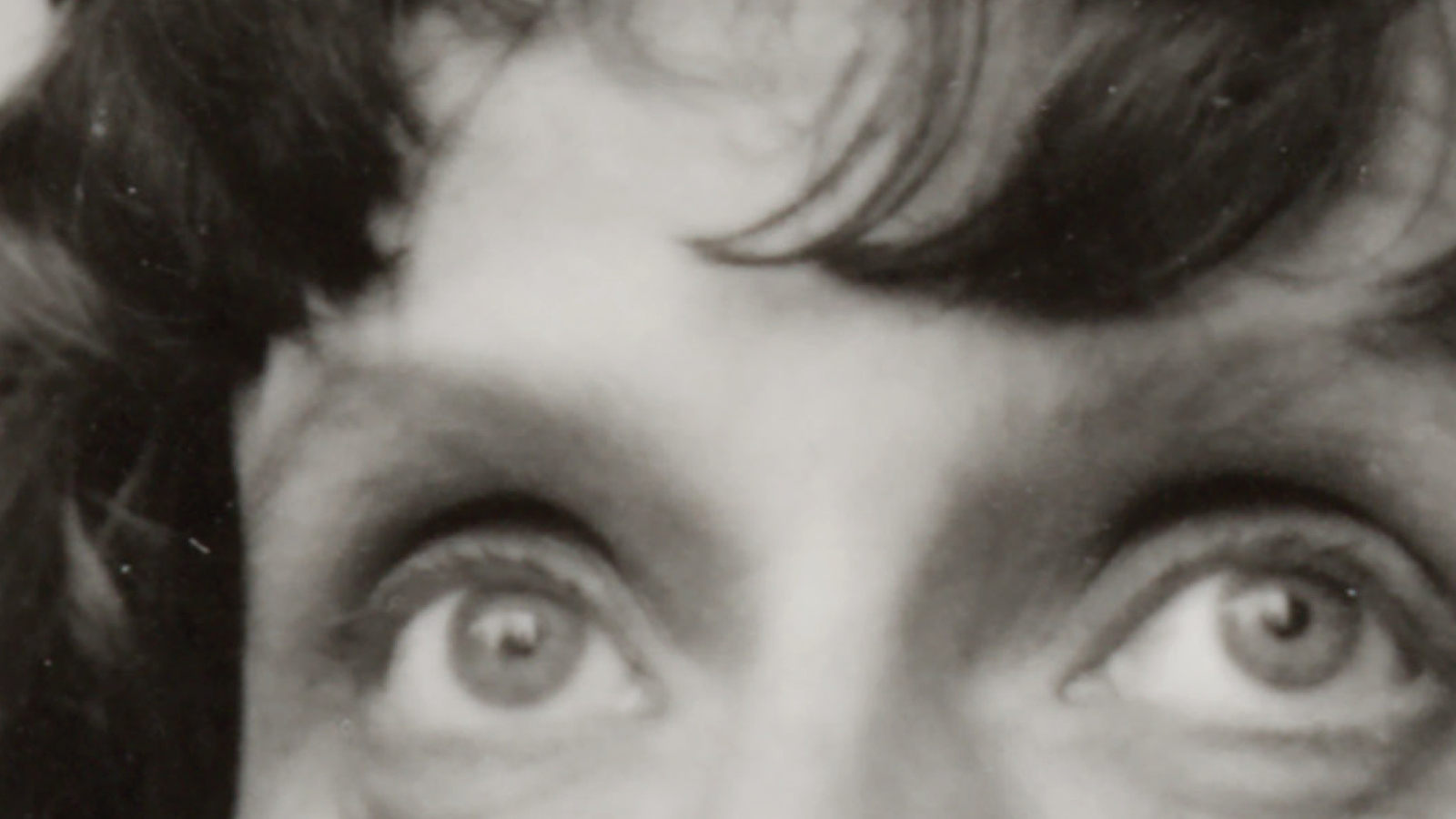 Kuvassa on Mirkka Rekolan silmät ja tummia kiharoita.  Kuva on musta-valkoinen.