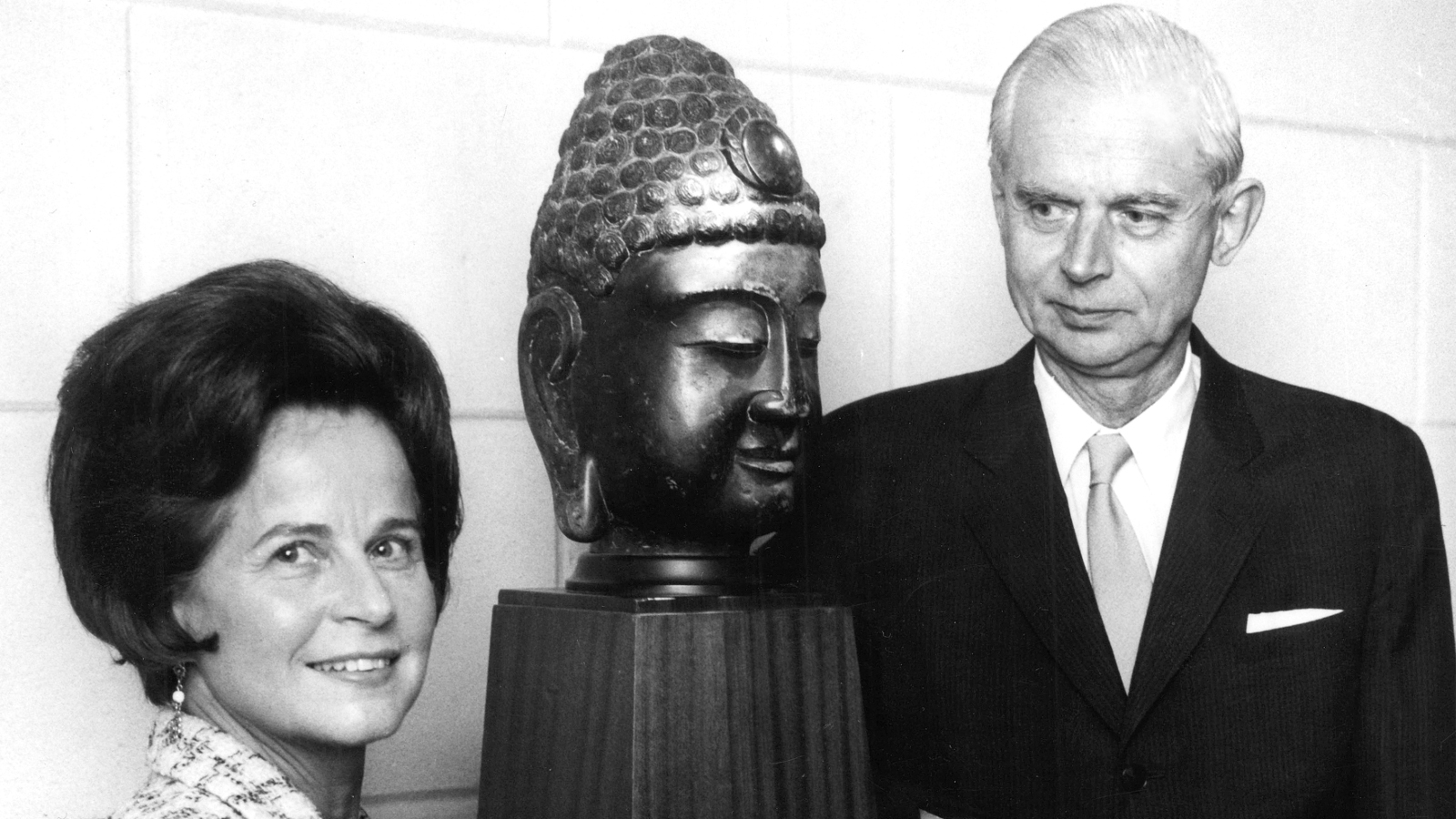 Kuvassa ovat Marie-Louise ja Gunnar Didrichsen buddhan päätä esittävän patsaan vierellä. Kuva on musta-valkoinen.