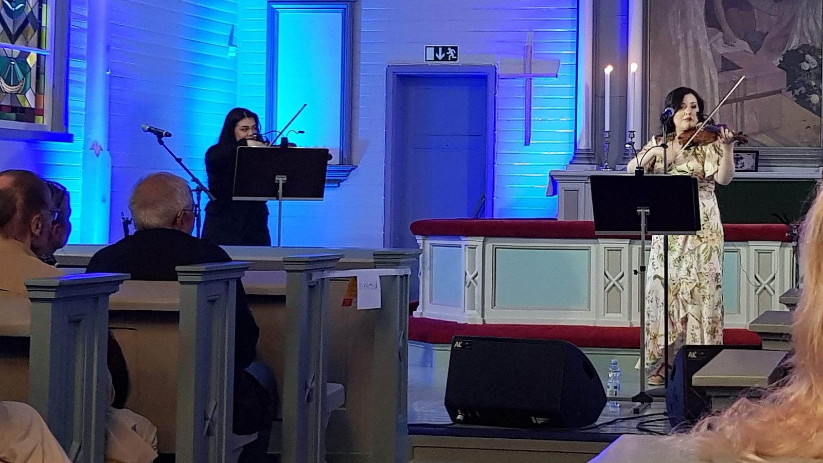 Kuvassa on vasemmalla Deidre Flores soittamassa viulua ja oikealla Diandra soittamassa myös viulua Virolahden kirkon etuosassa.
