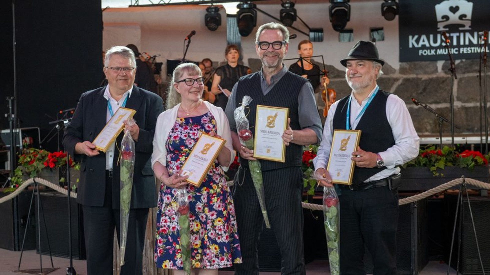 Kuvassa ovat vierekkäin pelimannit Aimo Hentinen, Anita Kaustinen, Juhani Lautamaja ja Patrik WEckman kädessään kunniakirja ja onnitteluruusu.