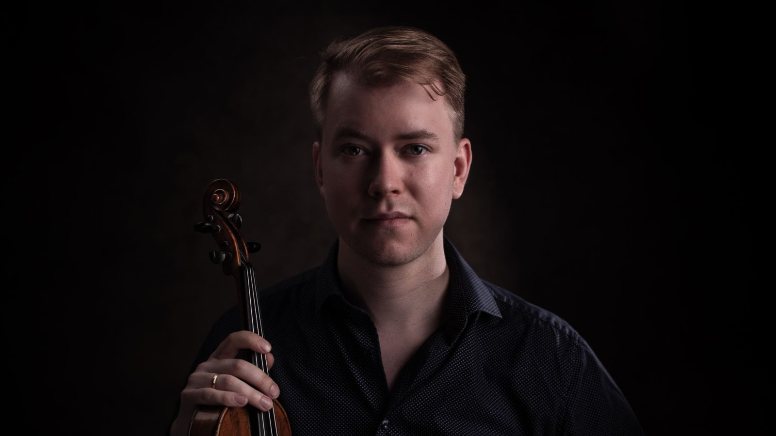 Kuvassa on Elias Lassfolk puolivartalokuvassa ja hänellä on viulu pystysuunnassa oikeassa kädessään.  Kuvan sävy on tumma.