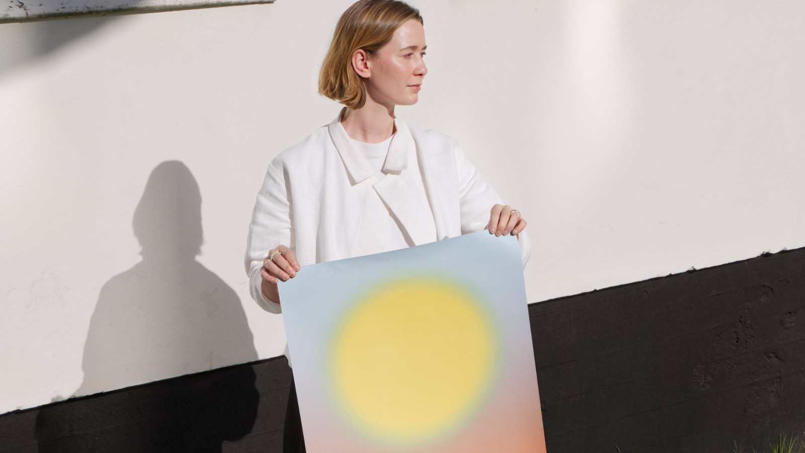 Kuvassa on Anna Meck, joka pitää edessään julistetta, jossa on iso keltainen pyöreä aurinko.