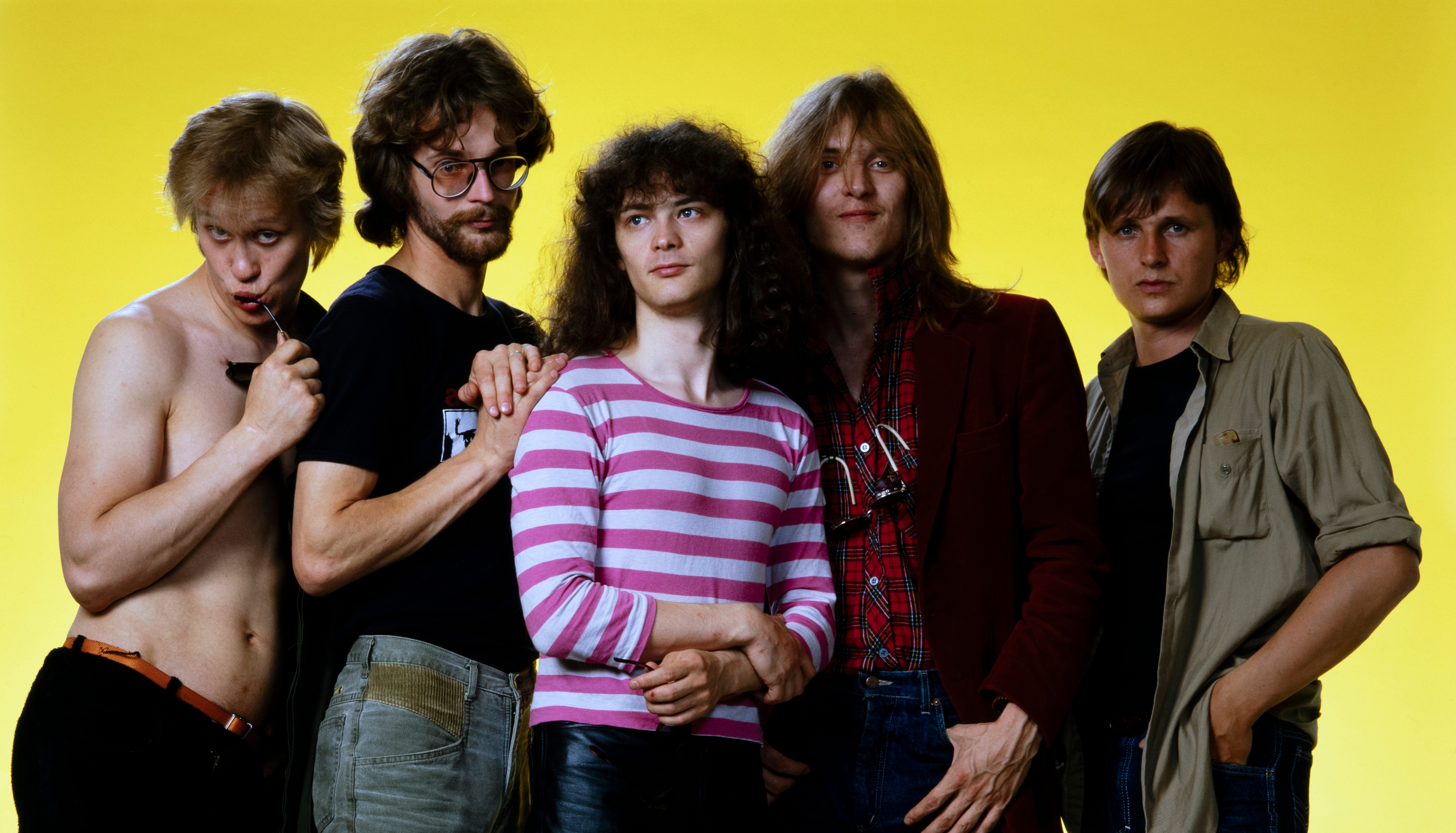 Kuvassa ovat Eppu Normaalin viisi jäsentä seisomassa.  Heistä vasemmalla olevalla Martti Syrjällä ei ole paitaa ja muilla on joko mustat tai keskimmäisellä valko-violetti t-paita.  Tausta on keltainen.
