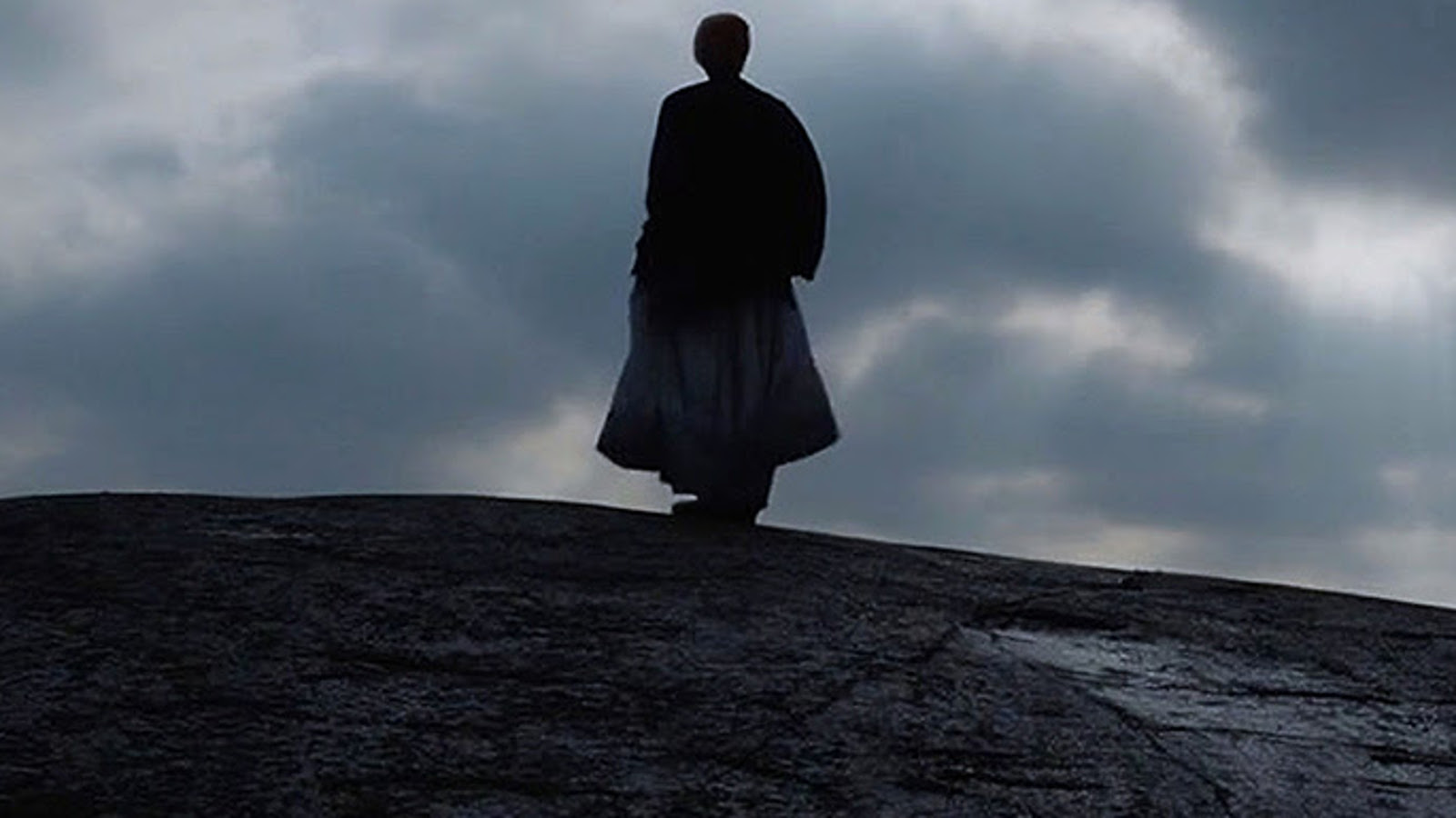 Kuvassa on tummalla kalliolla ja sen päällä tummassa pitkässä hameessa Maija katsomassa pois päin ja taivaalla tumman harmaan pilvistä. Kuva on osa levyn kannesta.