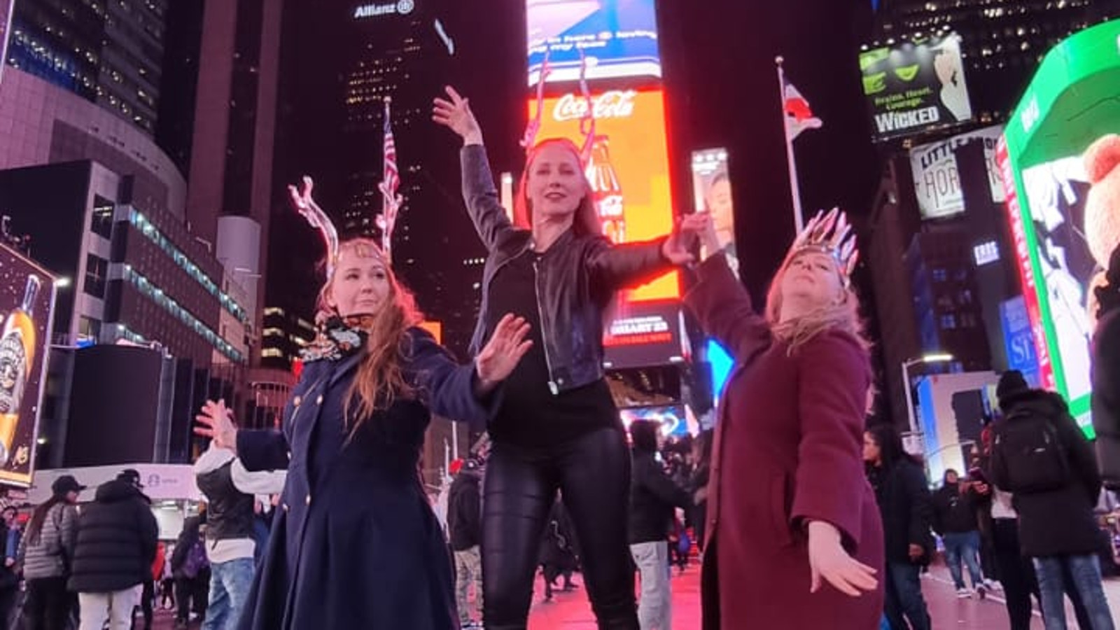 Kuvassa ovat Sini Marjuri, Mira Ollila ja Marja Hepo-aho keskellä New Yorkin katua takanaan värikäs pilvenpiirtäjä.  Heillä on lasikruunut päässään ja Ollilalla korkeat lasikengät.