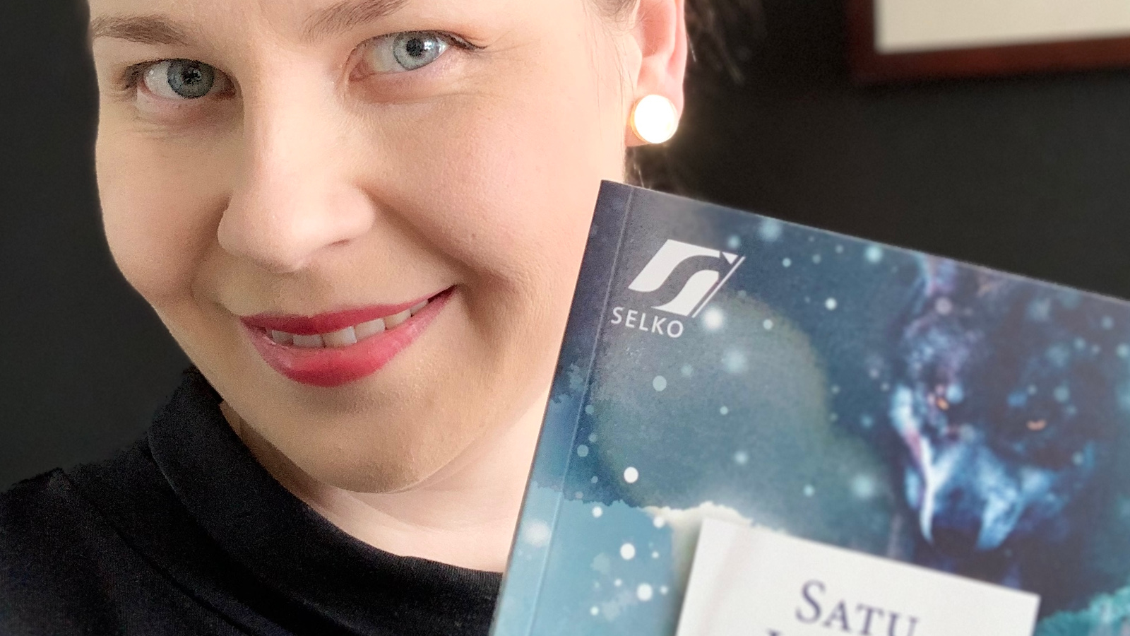 Kuvassa on Satu Leiskon kasvot ja alempana on vinosti osa kirjan kannesta, jossa on vaalean sinistä. Kuvan tausta on musta.