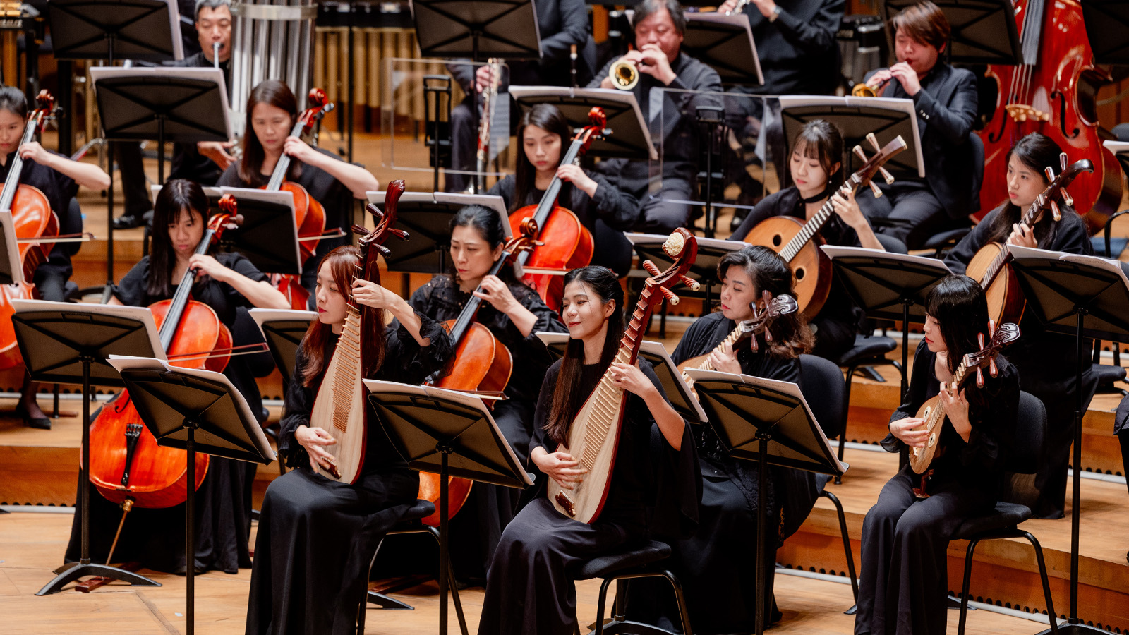Kuvassa on Kaohsiung Traditional Orchestra ja siinä on etualalla vinottain näissoittajia heidän traditionaalisen soittimensa kanssa mustissa mekoissa.