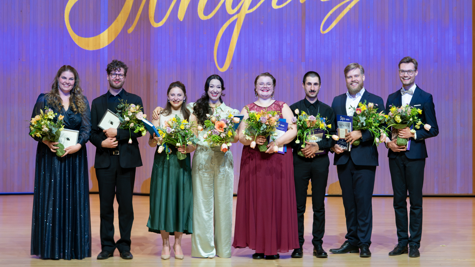 Kuvassa ovat Sibelius Singing -kilpailun voittajat, jossa naiset ovat pitkissä mekoissa ja miehet tummissa puvuissa.