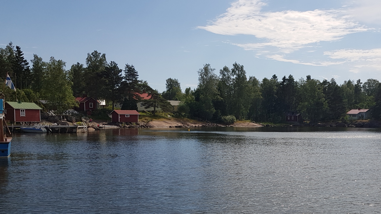 Kuvassa on vasemmalla rakennuksia Kuorsalon saaren kalliorannassa oikealla metsää. Etualalla on sinistä merta.