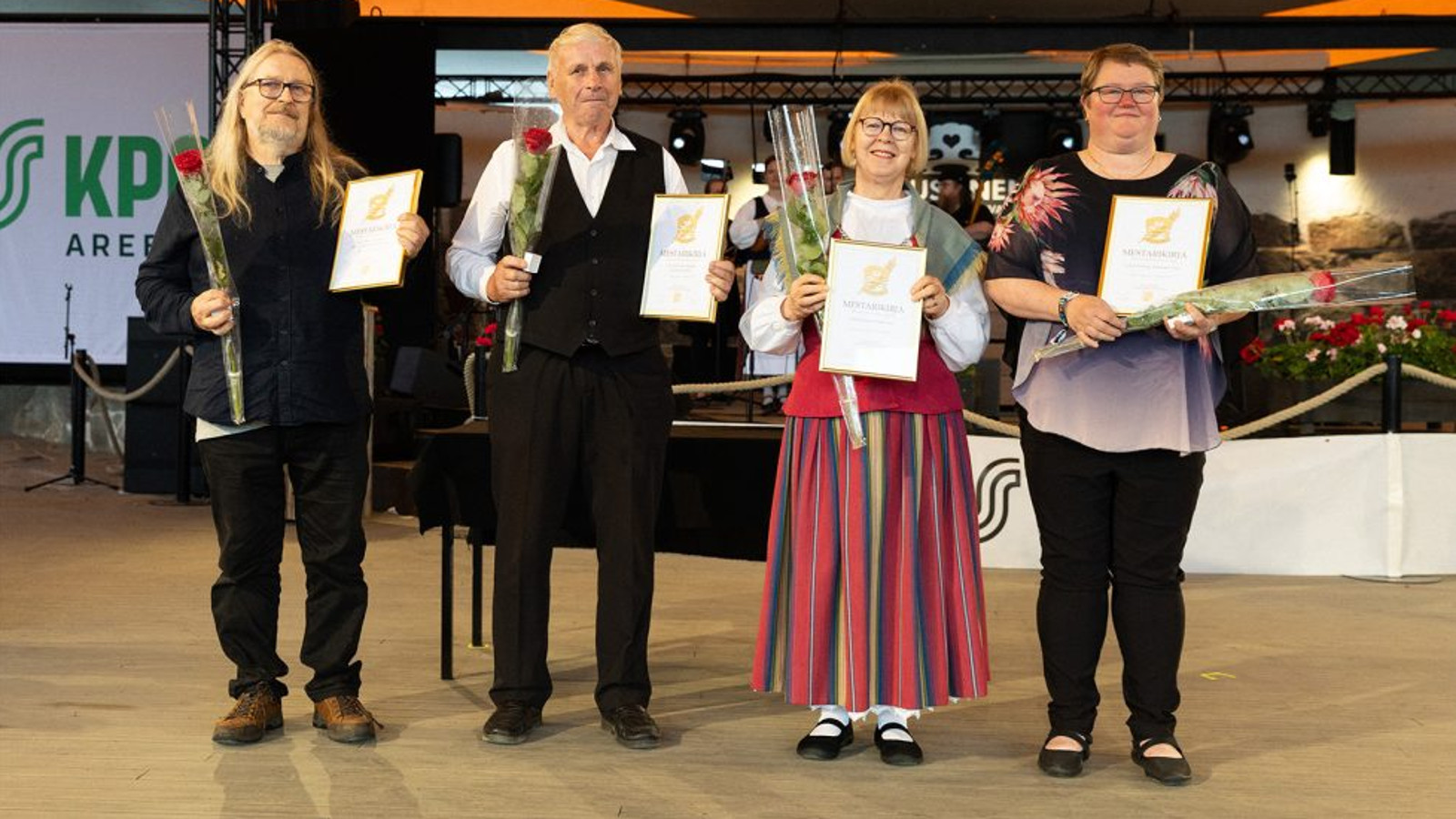 Kuvassa ovat vasemmalta Eero Myllymäri mustissa vaatteissa vieressään Rauno Nieminen.Oikealla Linnea Holmberg kansallispuvussa ja Liisa Kupiainen musta-harmaassa asussa. Jokaisella on ruusu ja kunniakirja kädessään.