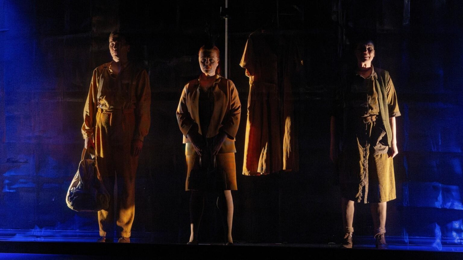 Kuvassa on neljä tummaa hahmoa ruskeissa vaatteissa ja valaistus on tummansinen ja tumma.