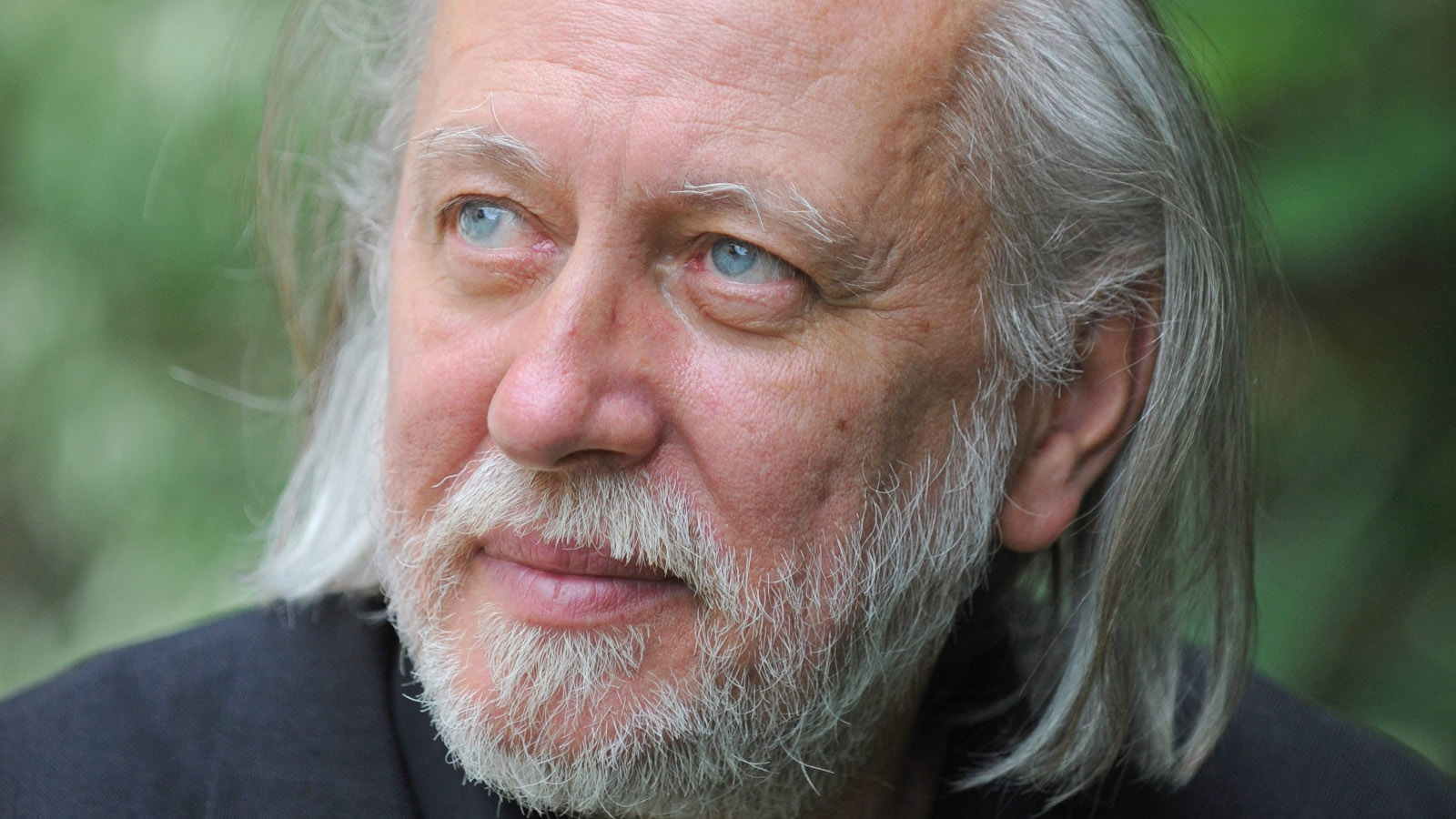 Kuvassa on ászlo Krasznahorkai kasvokuvassa.  Hänellä on vaaleat pitkät hiukset ja vaalea leukaparta