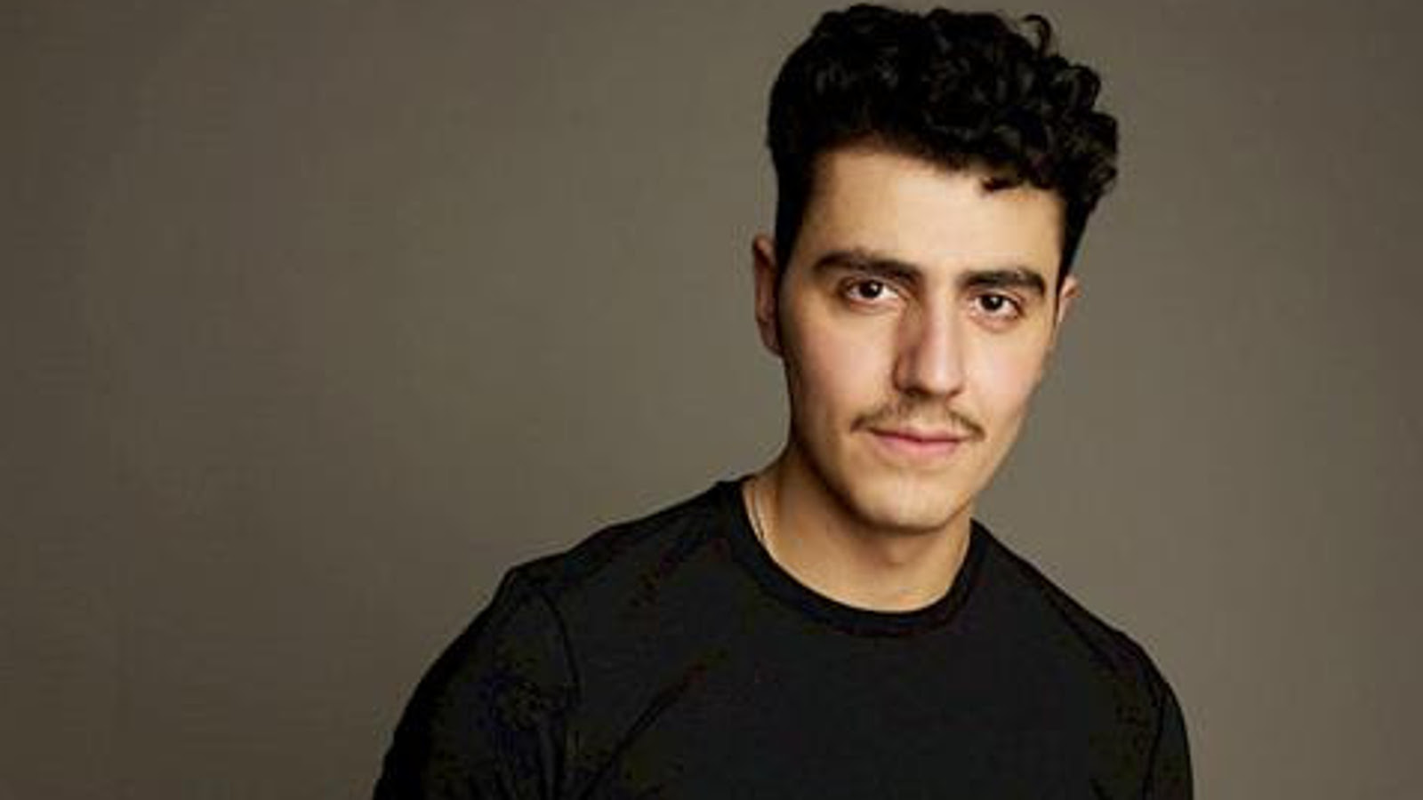 Kuvassa on Youssef Asad Alkhatibin puolivartalokuvassa ja hänellä on musta t-paita päällään. Tausta harmaan vihreää.