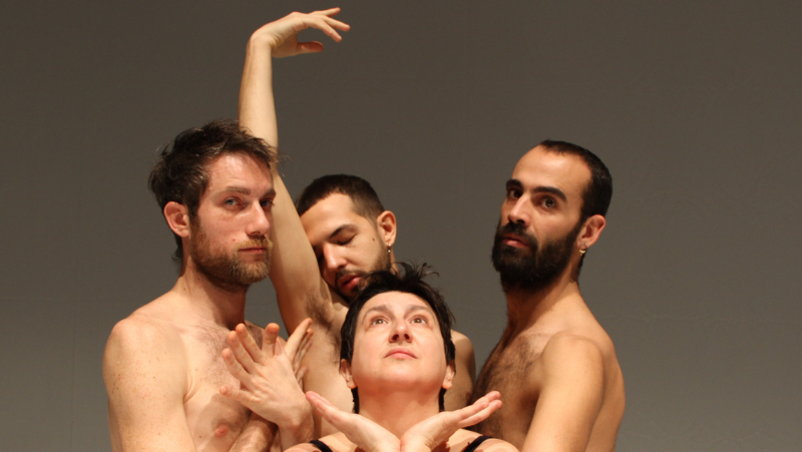 Kuvassa on viisi miestanssijaa tiiviinä ryhmänä ja kahdella heistä on yläruumis paljaana. Takana oleva ojentaa oikeaa kättään.