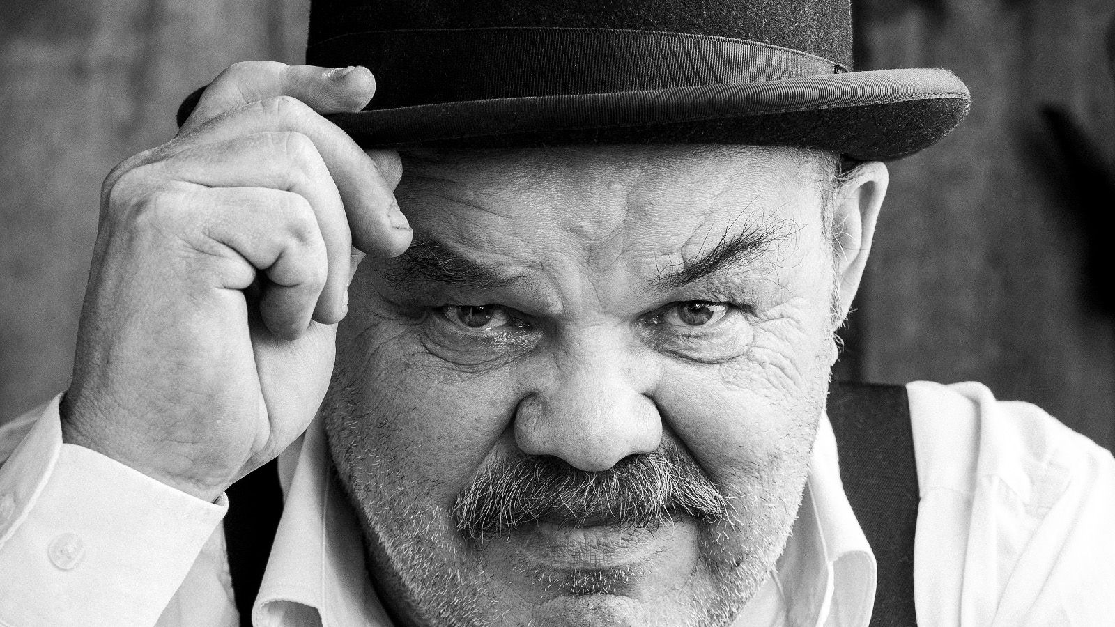 Kuvassa on Jaakko Teppo käavokuvassa ja hänellä on musa lierihattu päässään. Hän pitää oikealla kädellään kiinni hatun lieristä. 