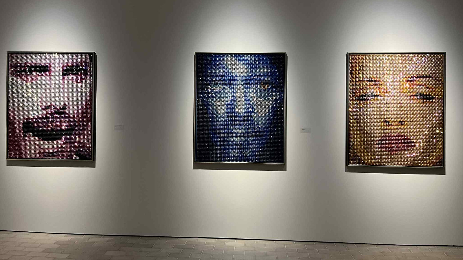 Kuvassa on kolme valokuvamaista teosta seinällä ja niissä on vasemmalta kahden miehen kasvot ja oikean puolimmaisessa on naisen kasvot. Kaikissa on verkkomaista pintaa. Tausta on harmaahko.