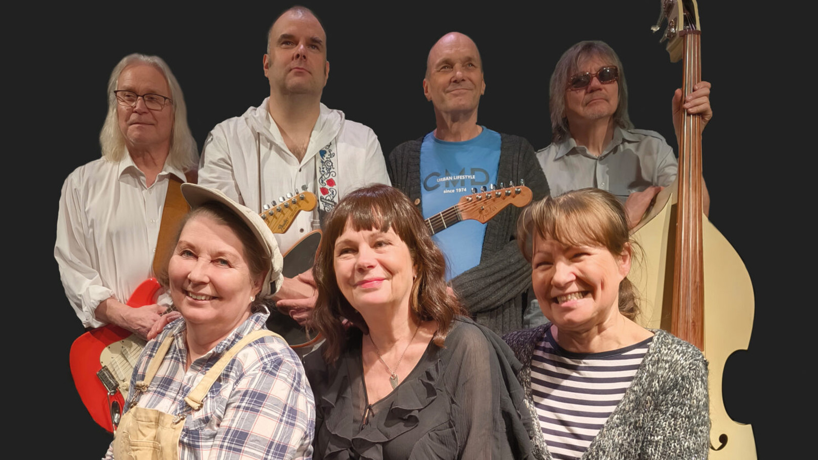 Kuvassa on takana neljä miestä seisomassa ja heillä on kahdella kitarat edessään. Oikealla olevalla on suuri vaalea basso vieressään. Miesten edessä on istumassa on kolme naista erivärisissä puseroissa.