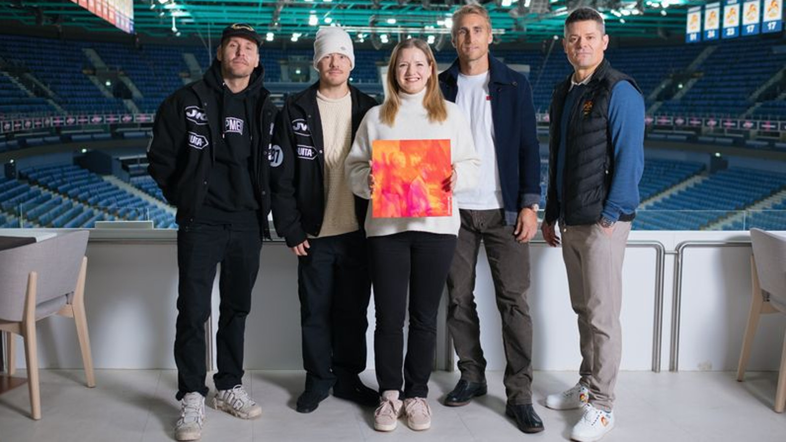 Kuvassa ovat vasemmalta VilleGalle, Jare ja Sari Aalto-Setälä kädessään oranssin pinkki levyn kansi ja Jokereiden edustajat seisomassa Jäähallissa taustallaan tyhjä katsomo.