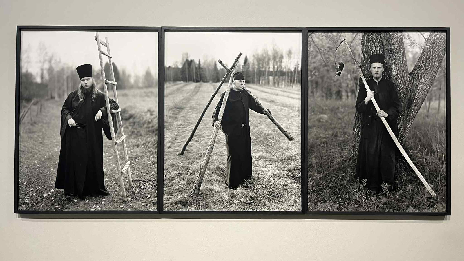 Kuvassa on kolme erillistä kuvaa ja niissä on munkki pitkässä kaavussa ja mustassa hatussa. Vasemmalla hän nojaa tikkaisiin, keskellä ympärillä on kolme tyhjää heinähankoa ja oikealla kuva seisomassa puun rungon edessä kädessään pitkä torvi. Kuvat ovat musta-valkoisia ja tausta on vaalean ruskea.