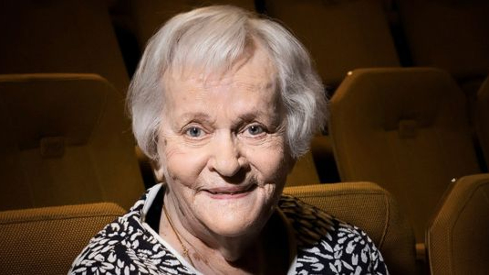 Kuvassa on Eila Roineen kasvokuva ja hänellä on vaalentuneet hiukset. Kuvassa näkyy musta-valkoisen puseron kaula-aukkoa. Taustalla on ruskeita teatterikatsoman tuoleja.