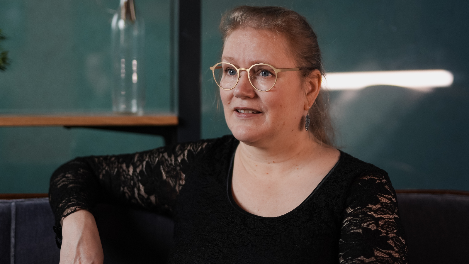  Kuvassa on Pipsa Lonka ja hän istuu puolivartalokuvassa. Hänellä on lilan värinen pusero päällään ja oikea käsi selkänojalla.