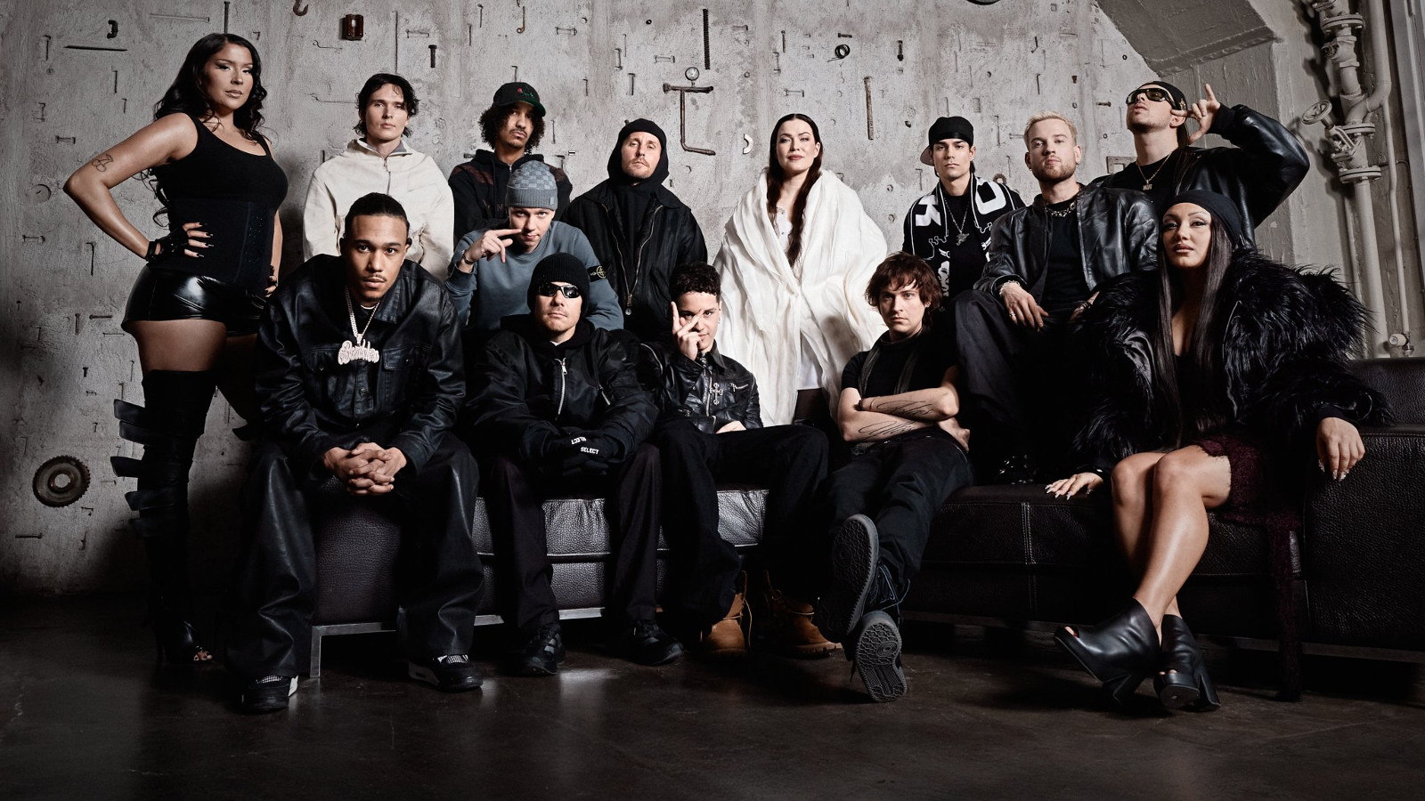 Kuvassa on kahdessa rivissä artistit ja takana on kahdeksen mies ja naisartistia, edessä viisi istumassa. Heillä on mustat vaatteet paitsi kadella valkoiset.