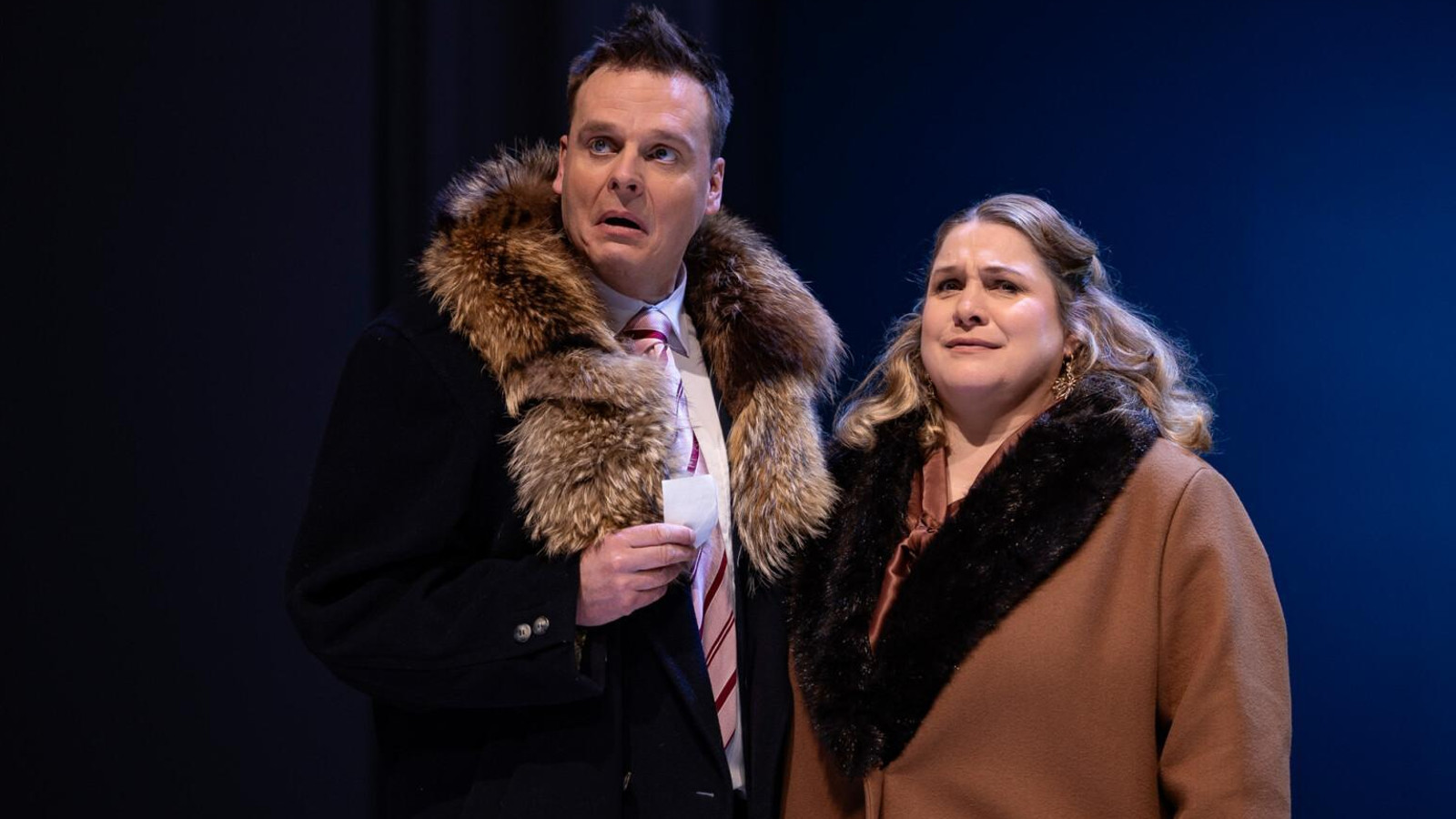 Kuvassa on Osku Haavisto isossa turkiskauluksisessa tummassa takissa. Hänen vieressään oikealla puolella seisoo Miia Maaranen turkiskauluksisessa ruskeassa takissa. Taust on tumma.