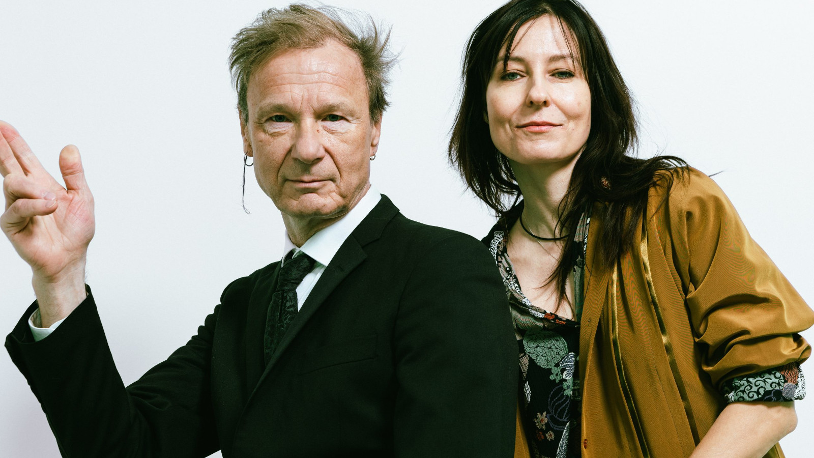 Kuvassa on vasemmalla Ismo Alanko puolivartalokuvassa mustassa takissa. Hänellä on oikea käsi nostettuna sivulle. Oikealla on Mariska ruskeassa villa takissa ja harmaassa puserossa.