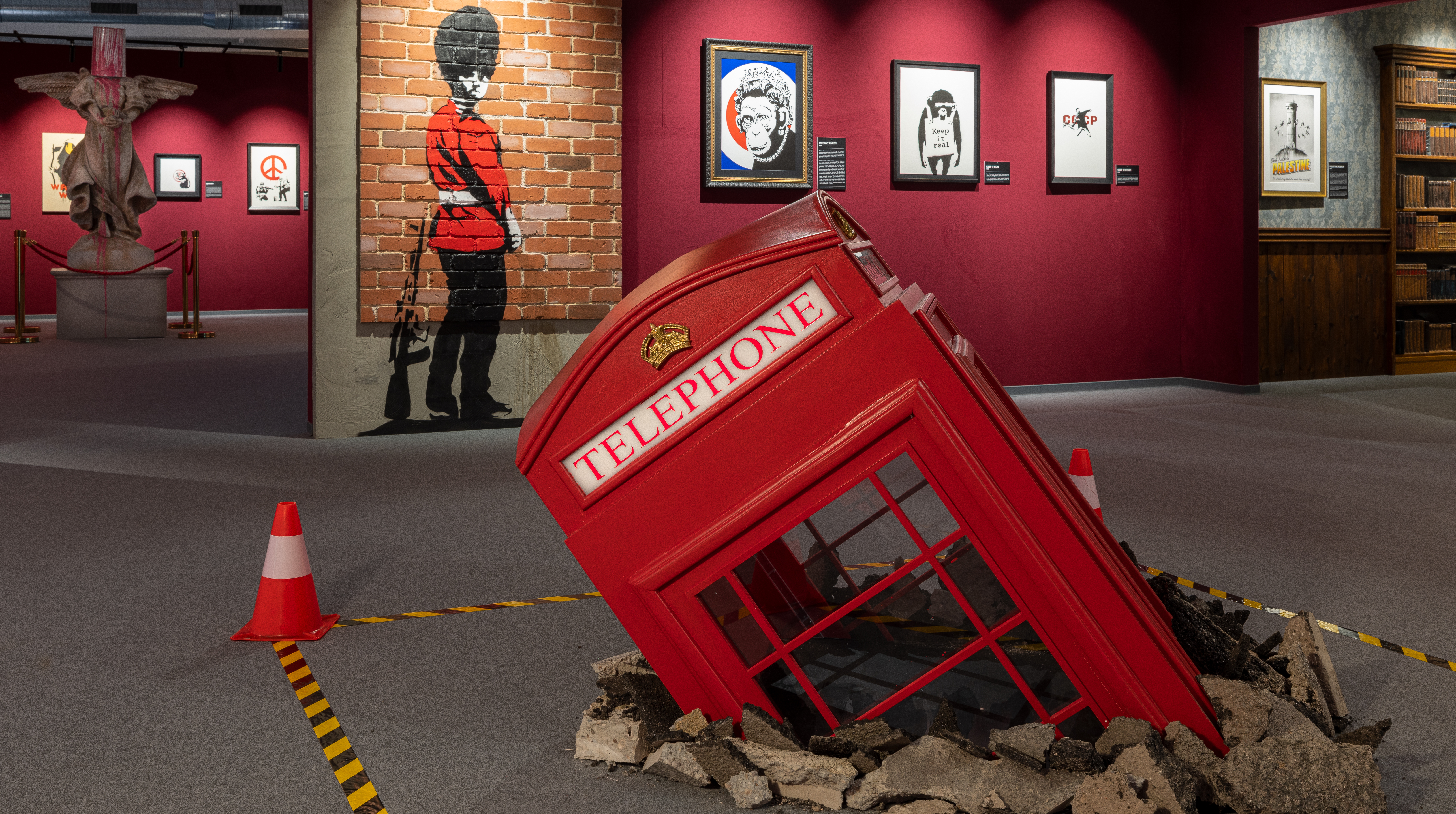 Kuvassa on ballerina seisomassa käsillään kivien päällä ja hänellä on jalat koukistettuna. Taustalla on harmaata betoniseinää. Maassa on vaalean ruskeita kiviä.