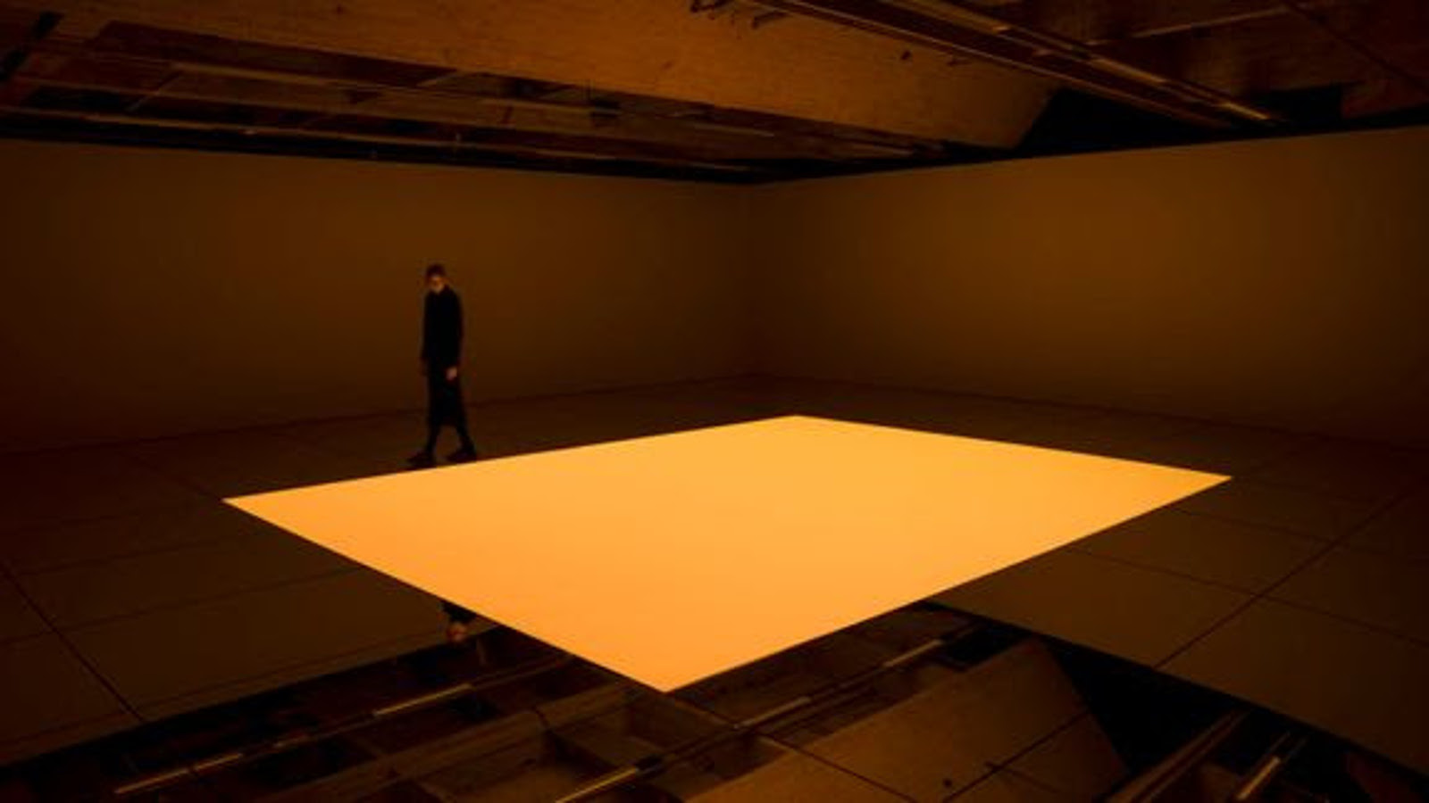 Kuvassa on ruskeassa tilassa kelluva, hiukan kaareva neliömäinen oranssi laatta.