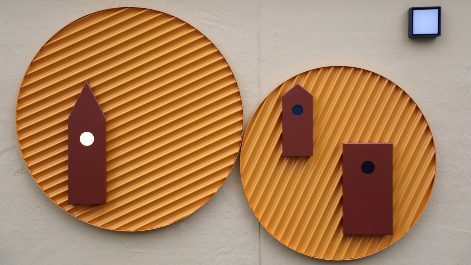 Kuvassa on kaksi pyöreä ja ruskehtavaa, kaiverrettua tasoa.  Niissä on tumman ruskeat tornin kuvat päällä. Tausta on harmaa.