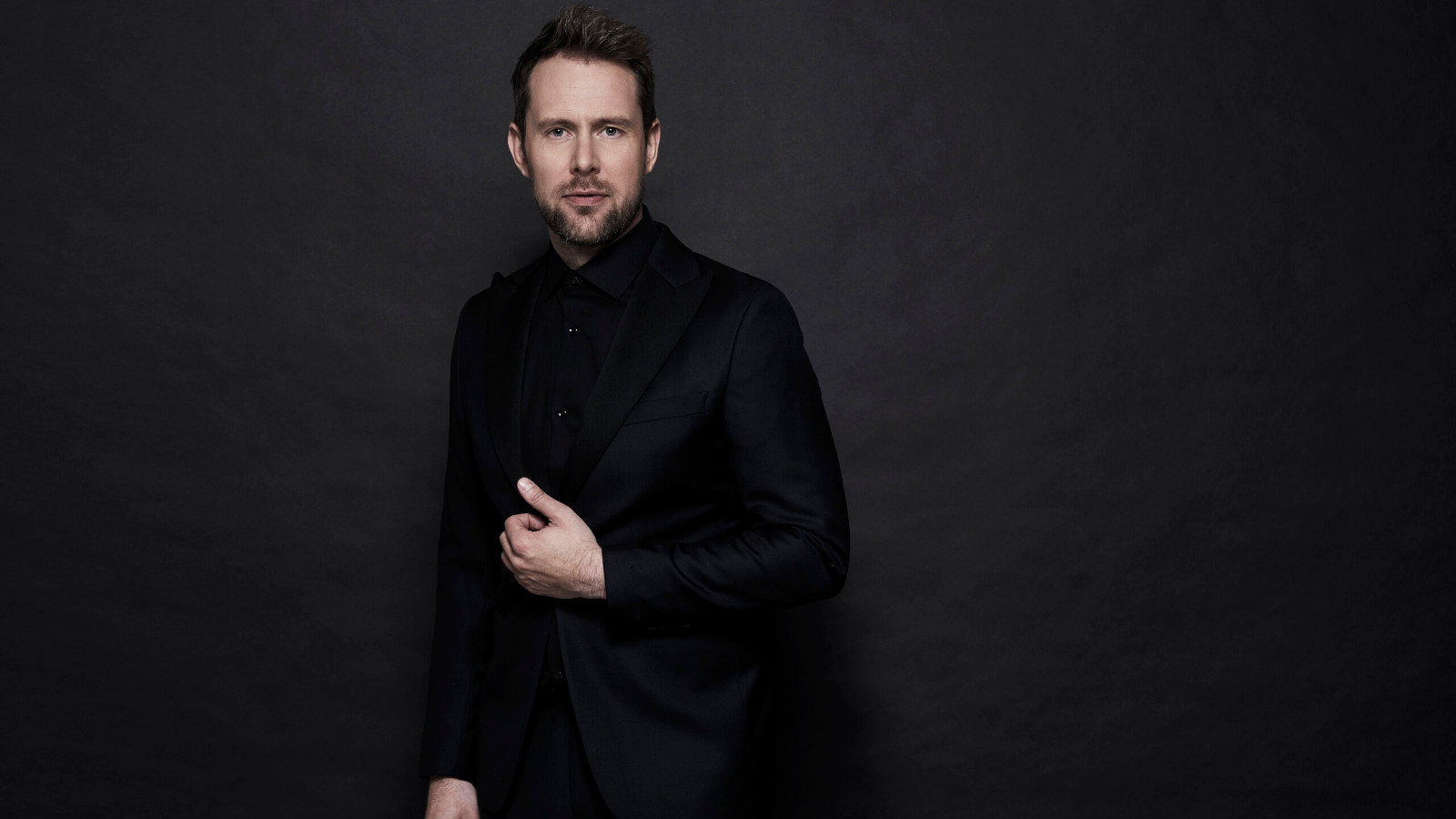 Kuvassa on Waltteri Torikka mustassa puserossa. Tausta on tumma ja kuvassa näkyvät torikan kasvot ja kädet.