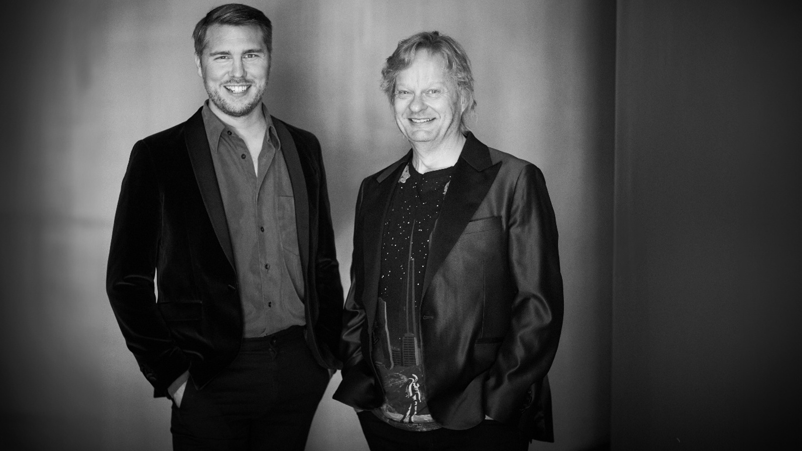 Kuvassa on seisomassa vasemmalla Aarne Pelkonen ja häenllä on musta takki päällään. Oikealla on Santtu-Matias Rouvali myös mustassa takissa. Kuva on musta-valkoinen.