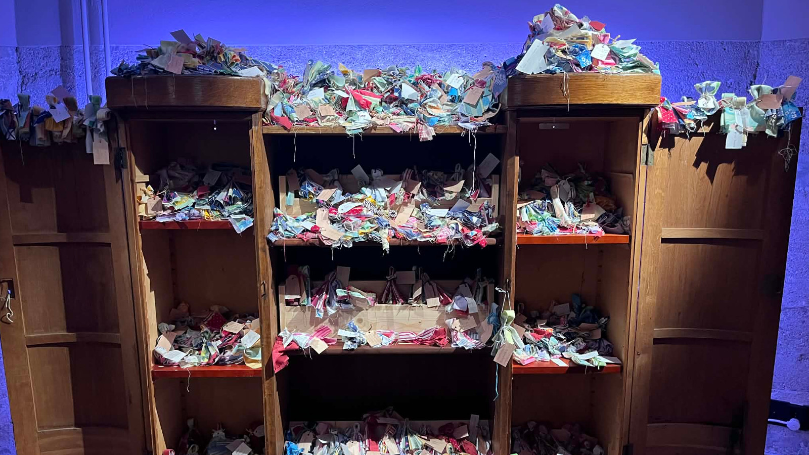 Kuvassa on ruskea hylly, jossa on vasemmalla ja oikealla kapeat hyllyt sekä keskellä. Hyllyillä on pientä silppumaista tavaraa.