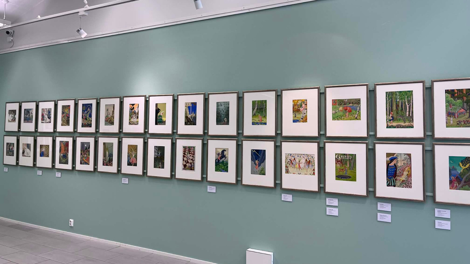 Kuvassa on vaalean turkoosilla pohjalla tauluja kahdessa on pitkässä rivissä.