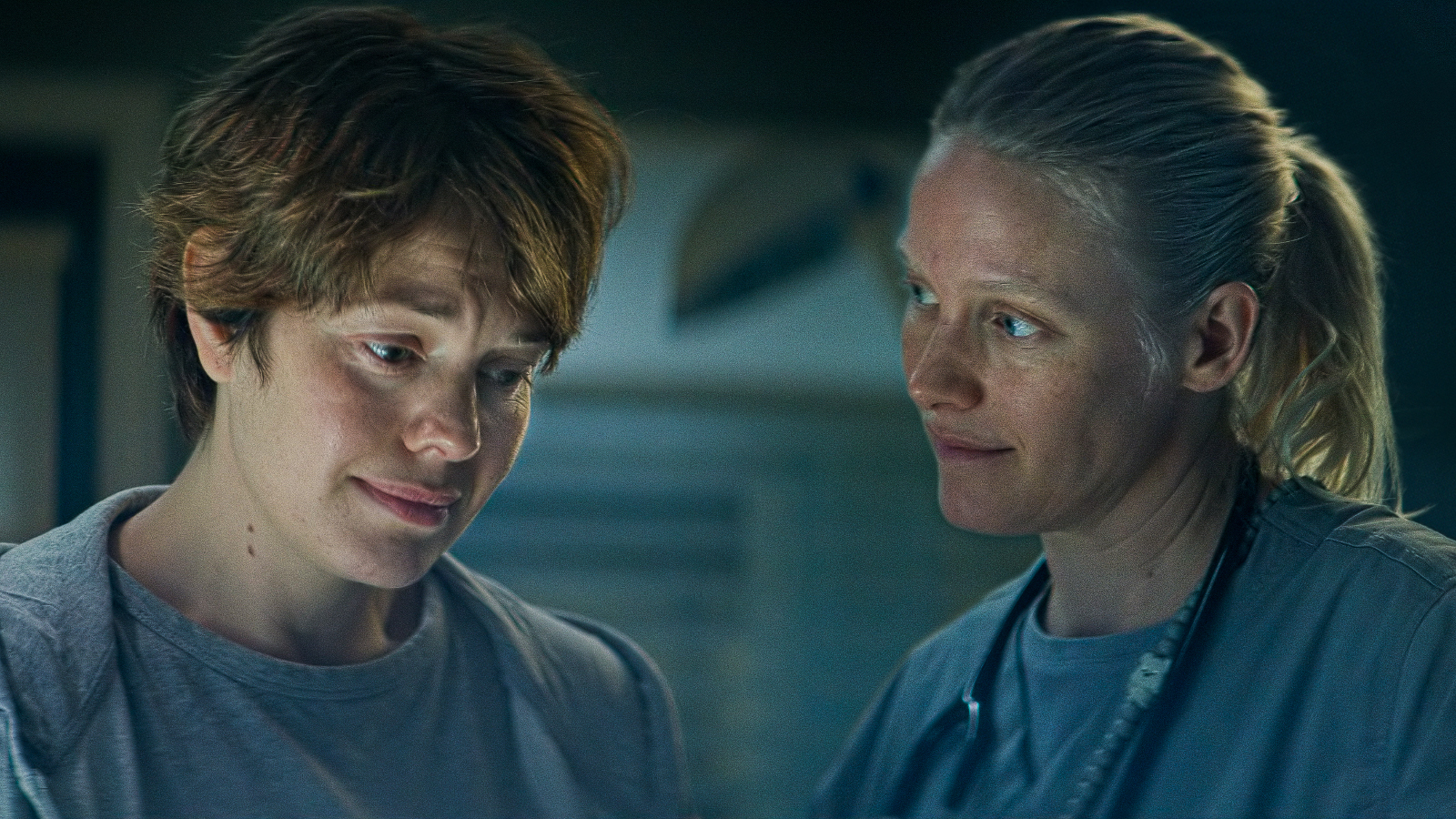 Kuvassa on vasemmalla puolivartalokuvassa Oona Airola katsomassa alaspäin ja oikealla Laura Birn katsoo Oona Airolaa. Molemmilla on vaalean siniset vaatteet.  