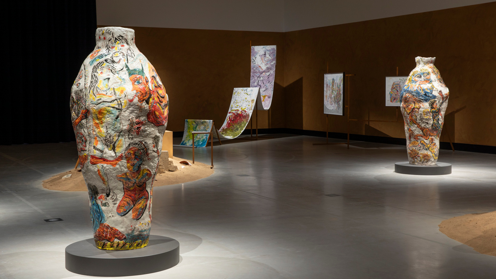 Kuvassa on vasemmalla iso värikäs ruukku ja oikealla taaempana toinen. Takana on liukumäkimäinen ja kaksi jyrkkää ylämäkeä.