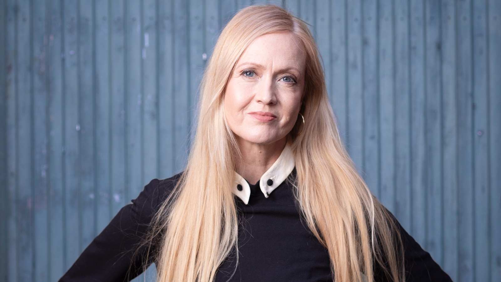 Kuvassa on Eveliina Talvitie puolivartalokuvassa ja hänellä on musta pusero päällään. Hänellä on pitkät vaaleat hiukset. Tausta on sininen.